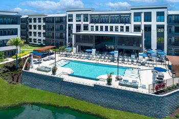 a large pool with lounge chairs and umbrellas in front of a building  at Ironwood Flats, Florida, 33511